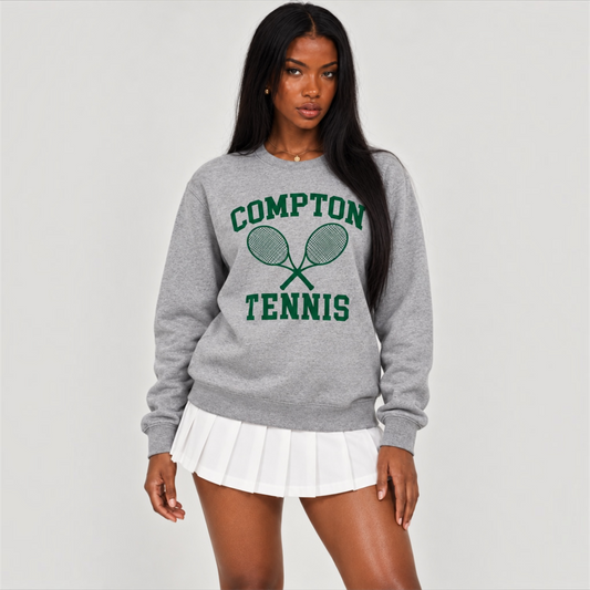 Model wearing the heather gray DonDeMarco women’s Compton Tennis sweatshirt with a white pleated tennis skirt, studio front view