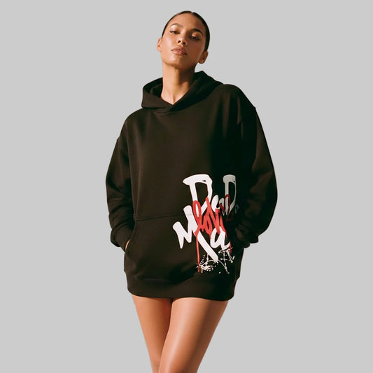 Person wearing a black hoodie with graphic design on a neutral background